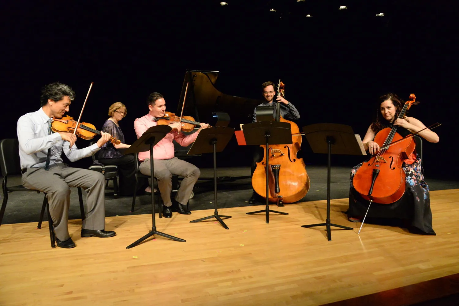 A pianist and four string players, one on double bass, playing on stage