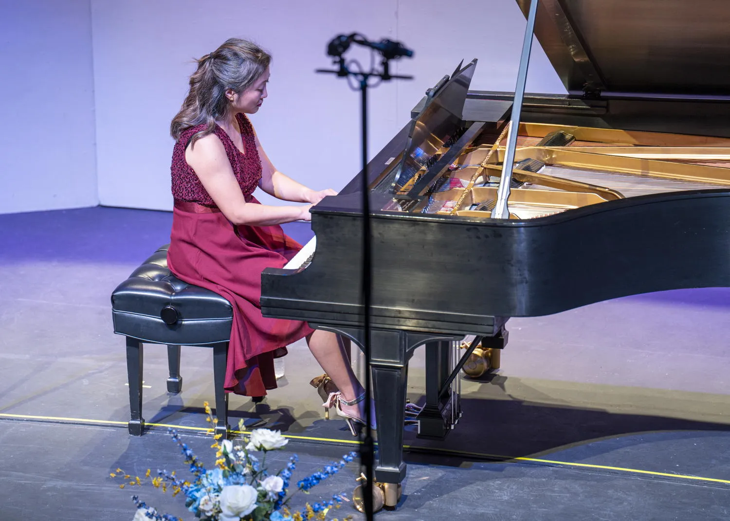 A pianist in a red dress playing a grand piano on stage