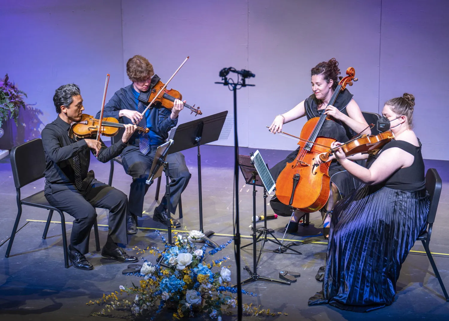 A string quartet performing on a stage lit in purple