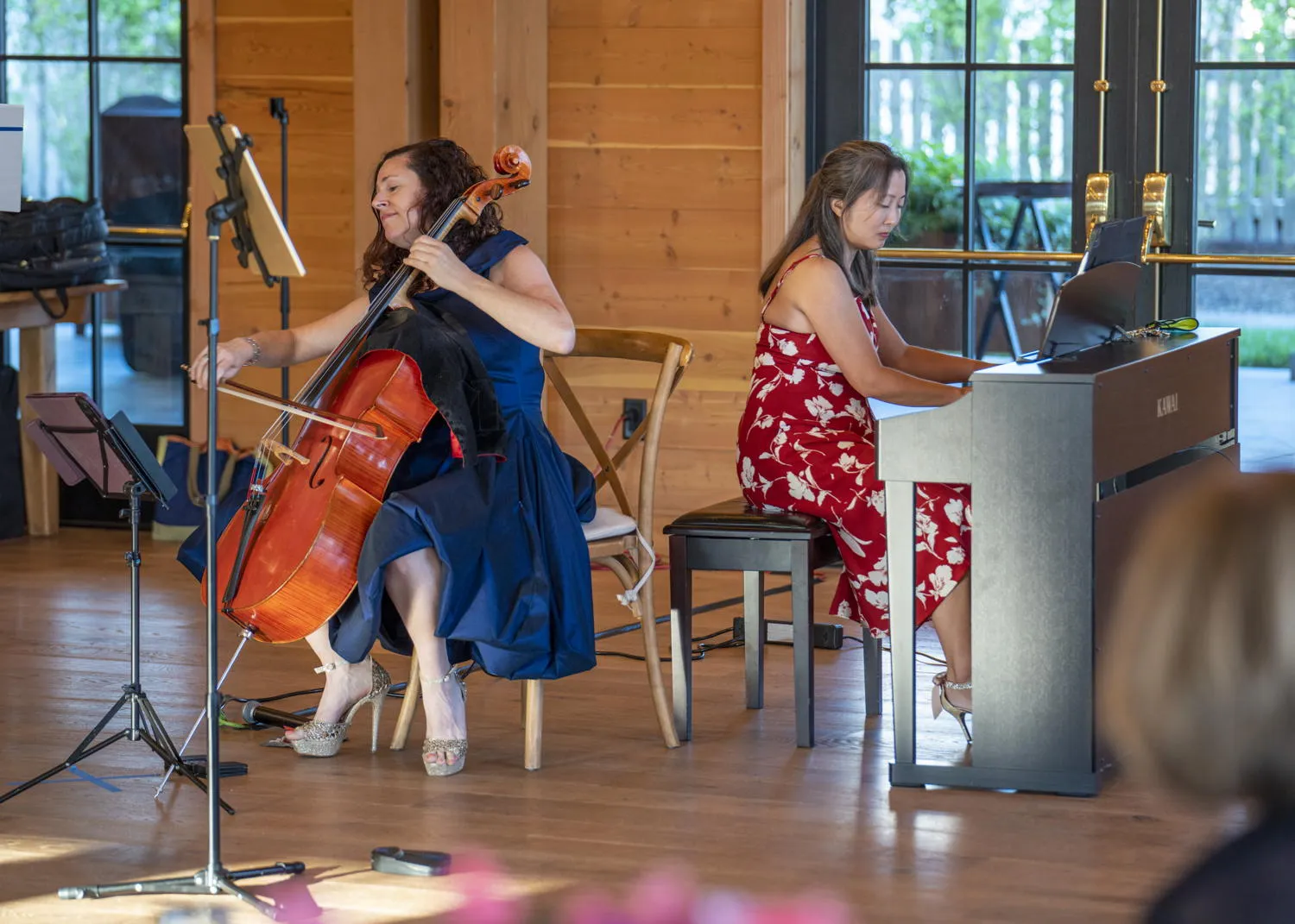 A cellist and a pianist performing in a wood-paneled hall