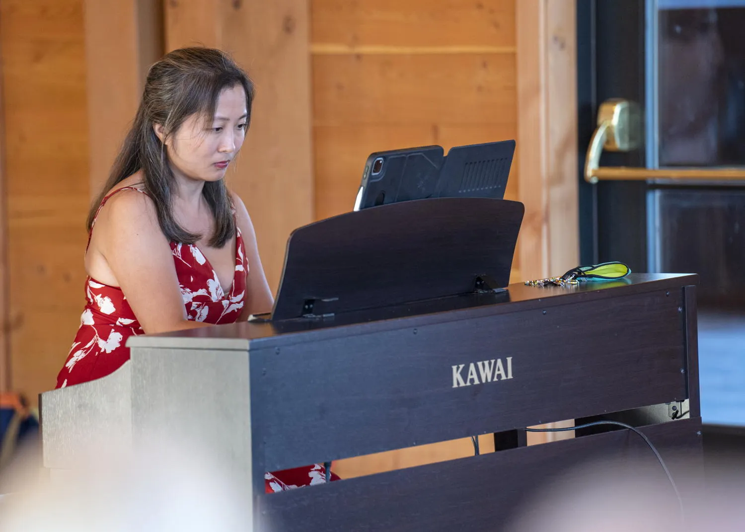 A pianist playing a digital piano in a wood-paneled room