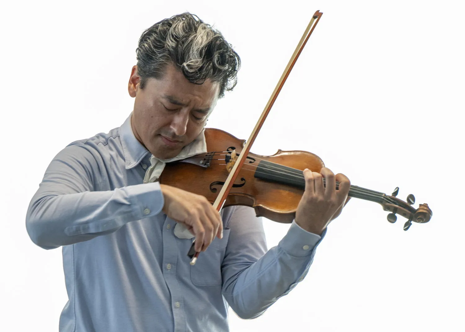 A violinist playing with eyes closed against a bright window