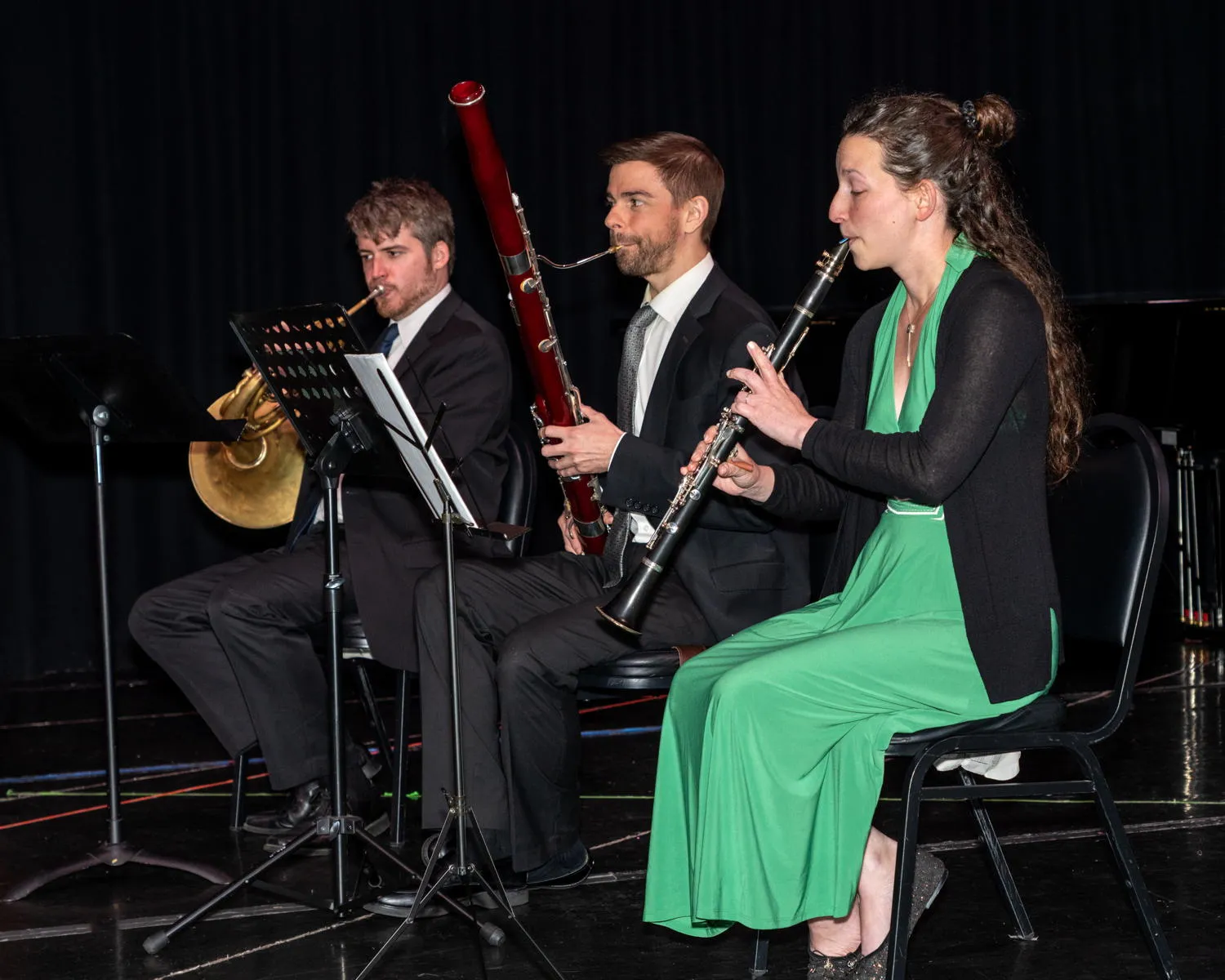 A horn player, a bassoonist and a clarinetist performing on stage