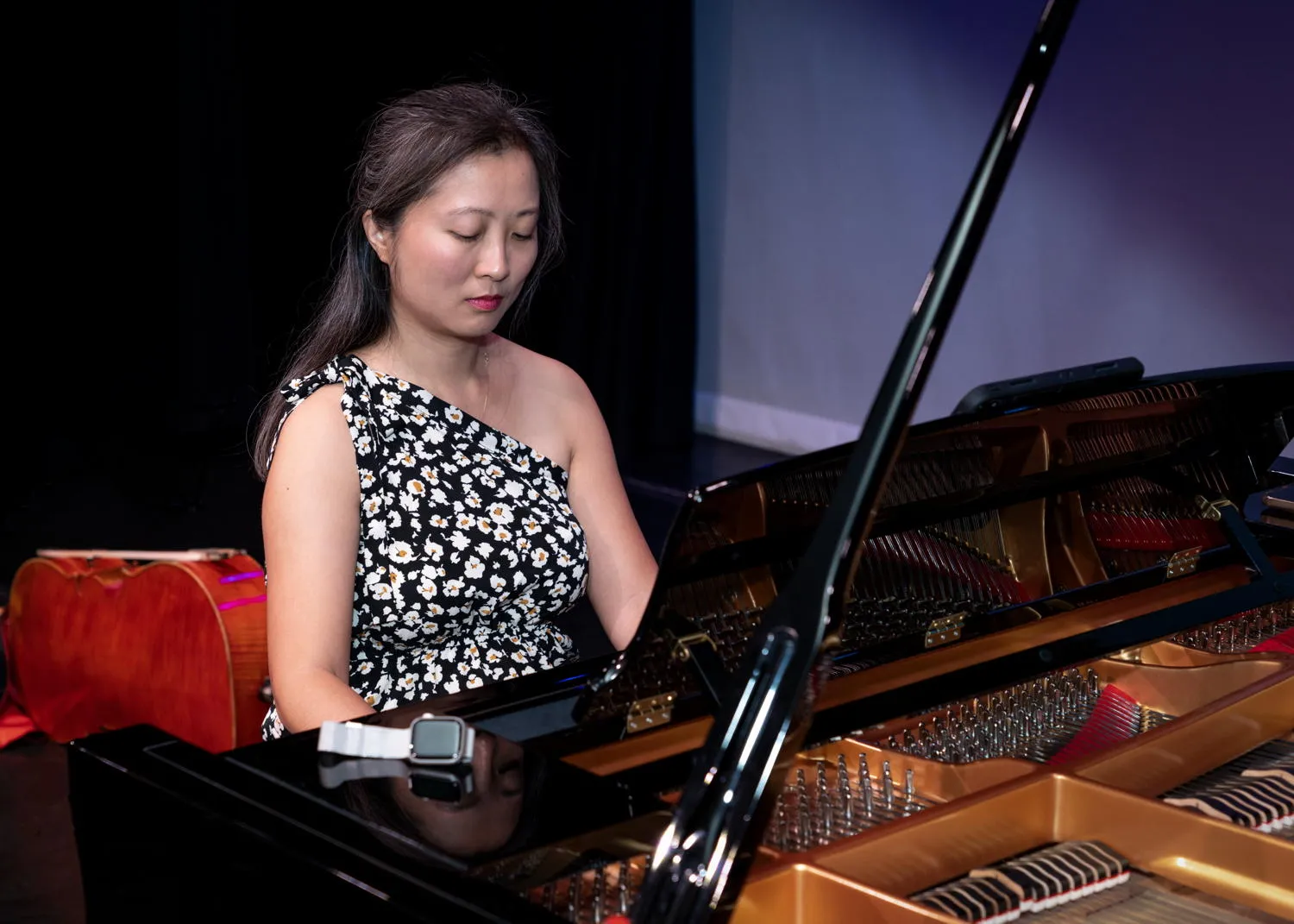 A pianist playing an open grand piano on stage