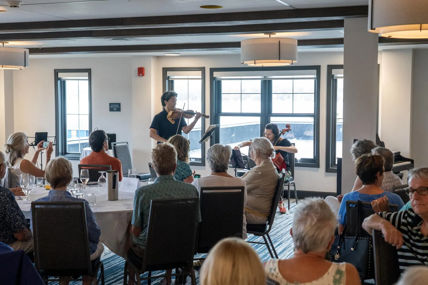 Guests at round tables listening to a violin and cello duo