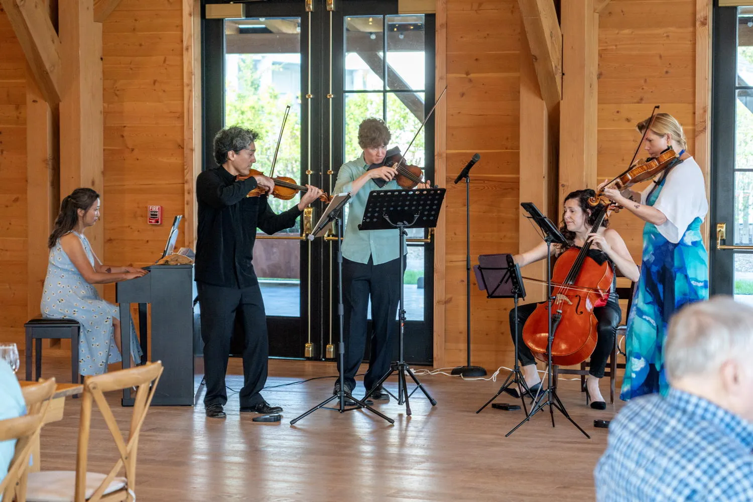 A pianist and four string players performing in the timber hall at the Lake House on Canandaigua