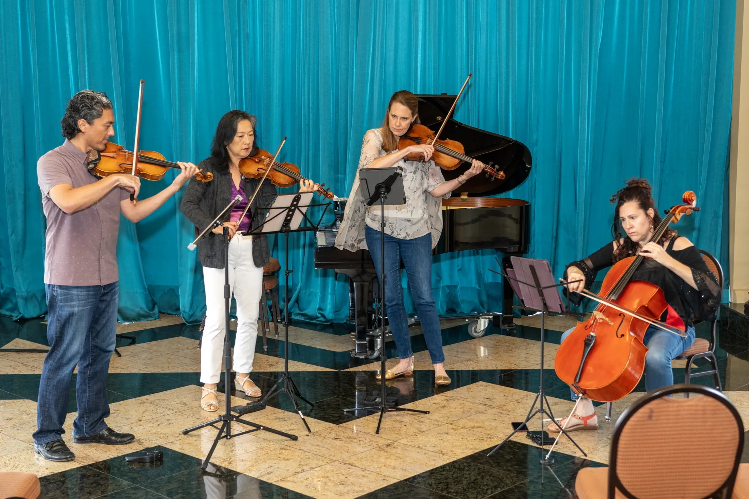 A string quartet playing in front of a teal curtain