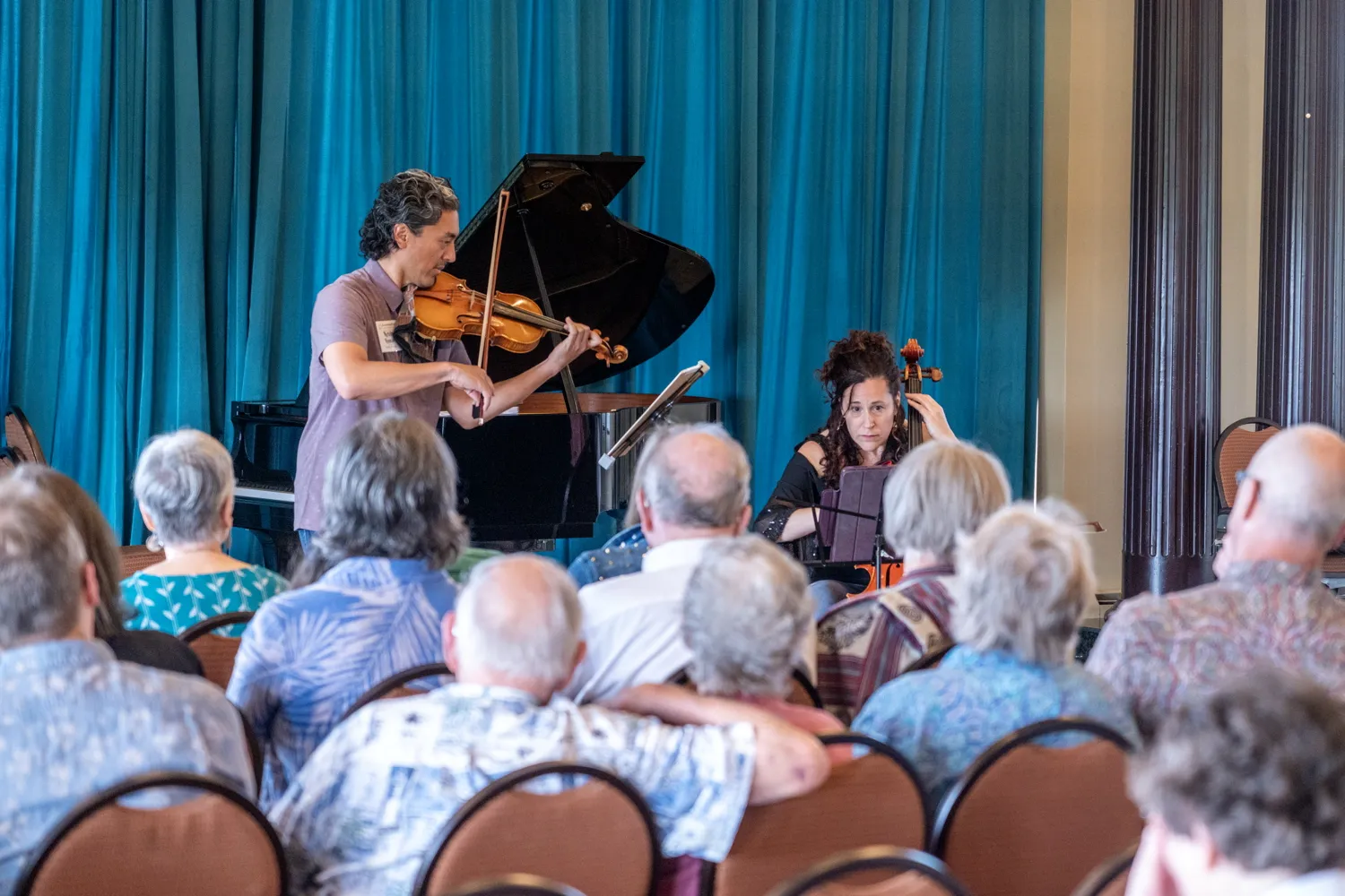 A violinist and a cellist playing for a seated audience