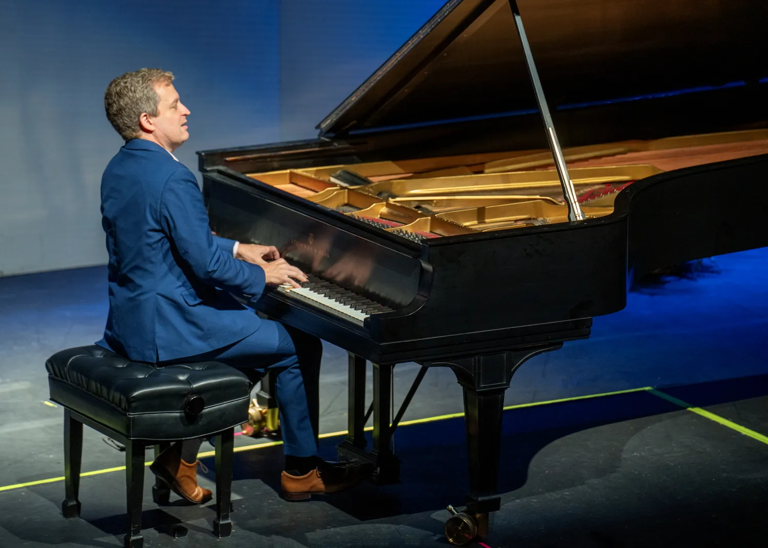 Andrew Armstrong at the piano under blue stage light