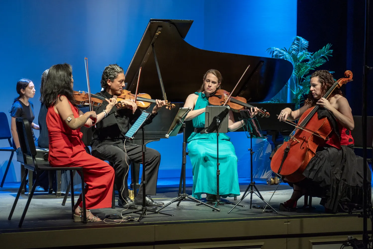 A piano quintet on stage under blue light