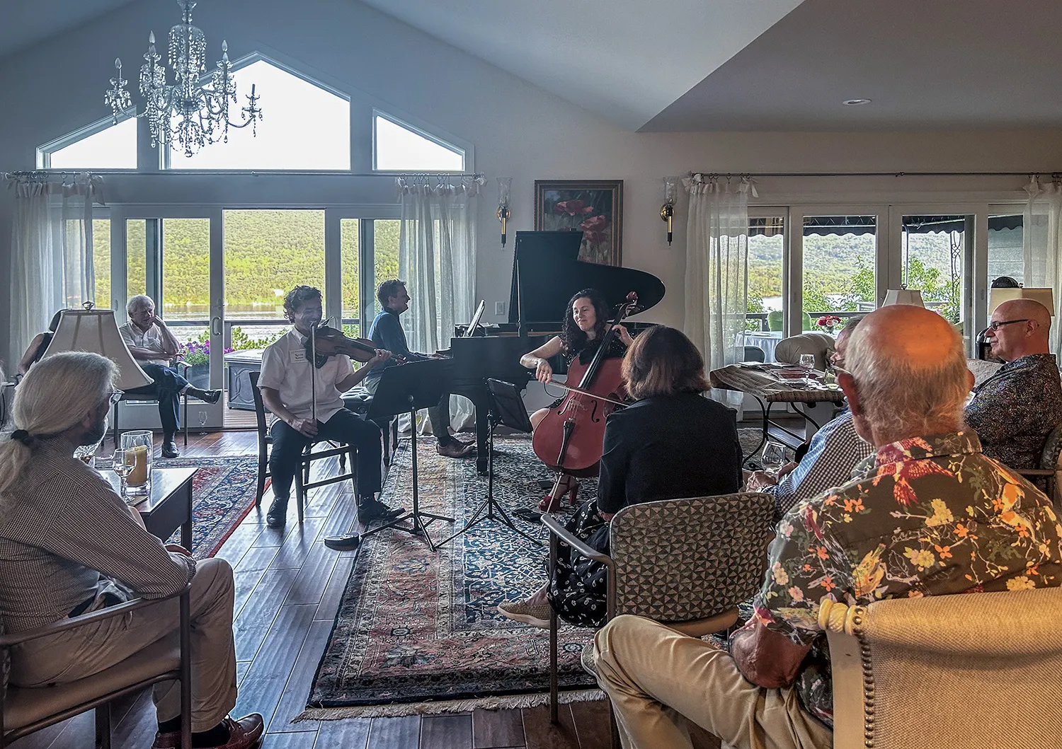 A violinist, pianist and cellist playing in a living room above the lake