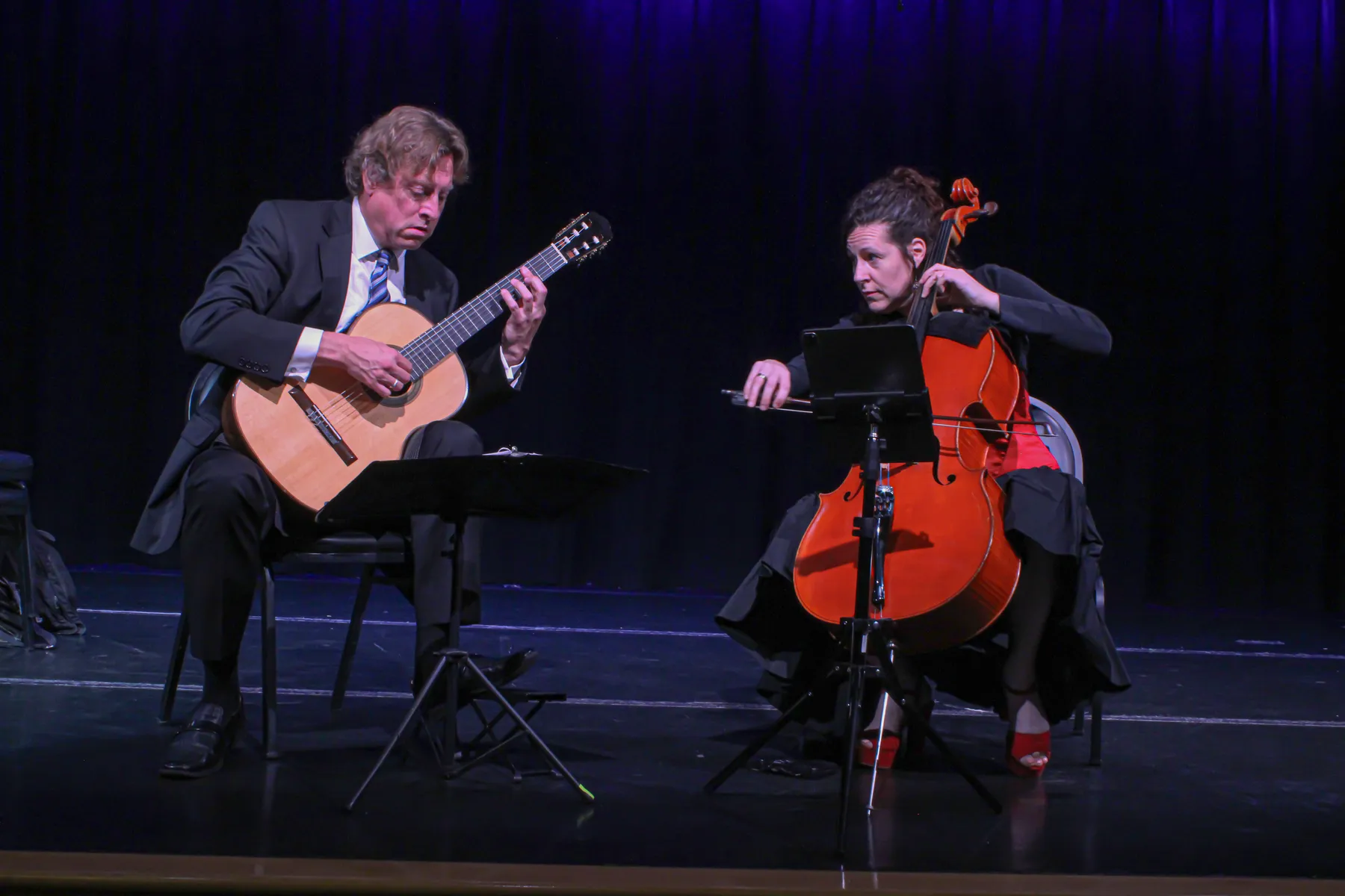 Jason Vieaux and a cellist playing a duo on a dark stage