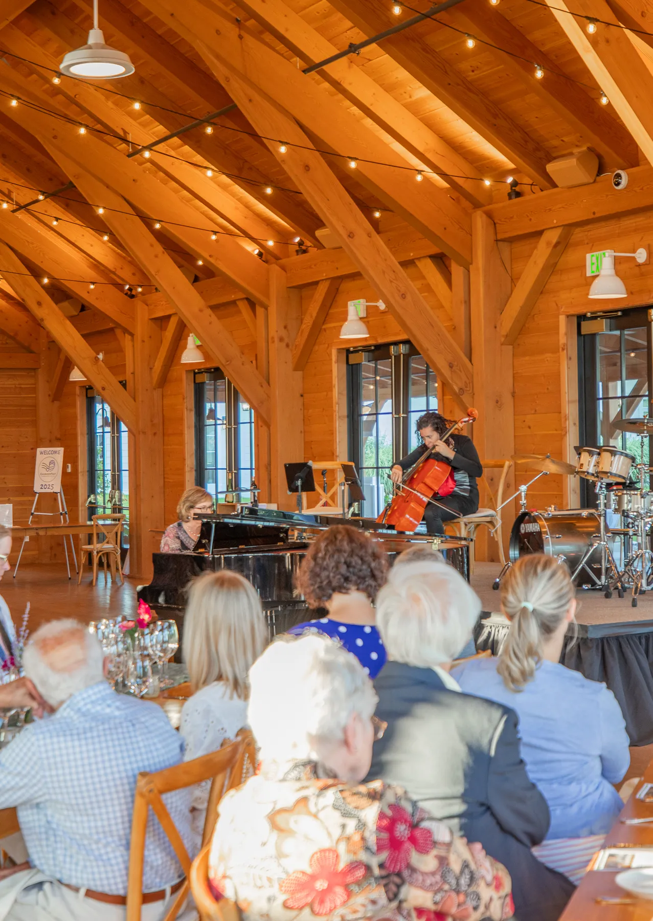 A pianist and a cellist performing for dinner guests under the timber roof
