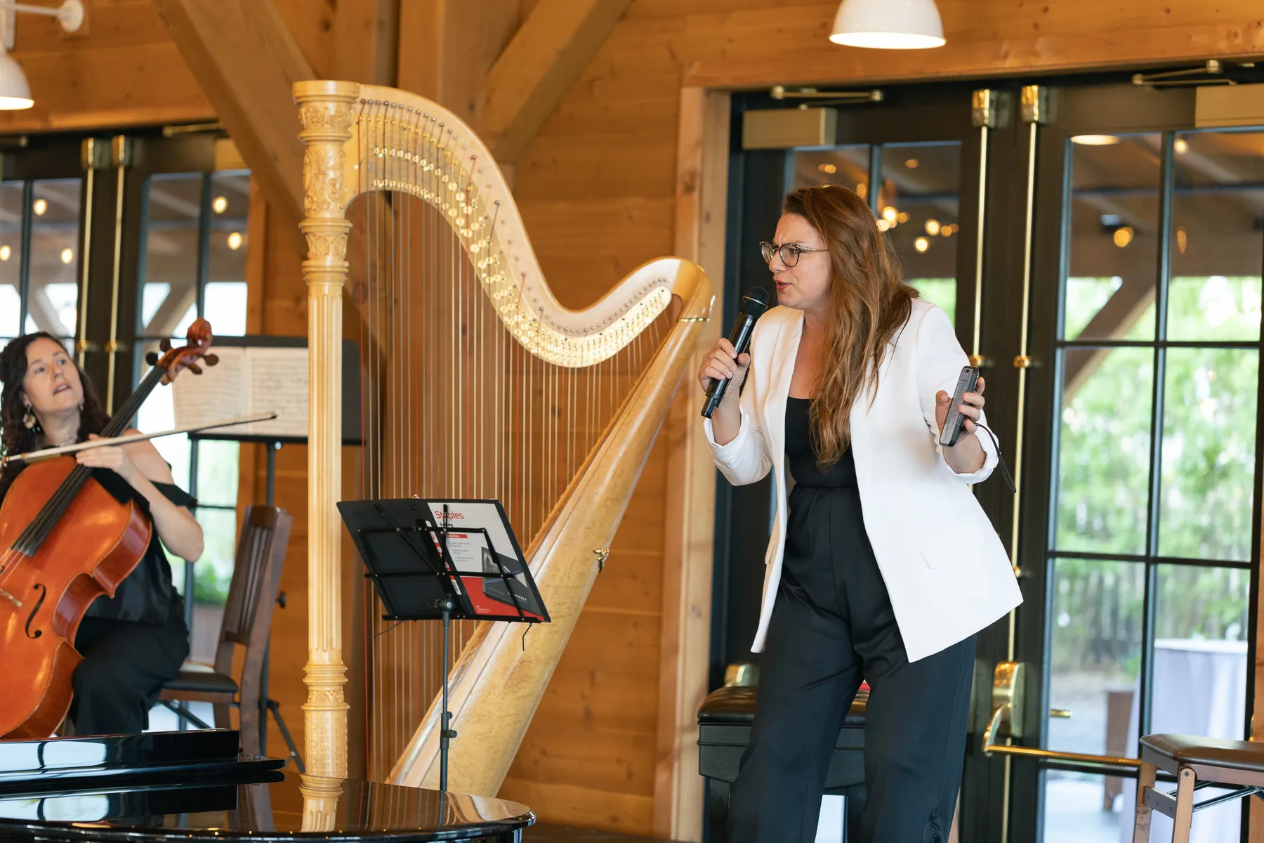 A speaker at the microphone beside the harp at The Lake House