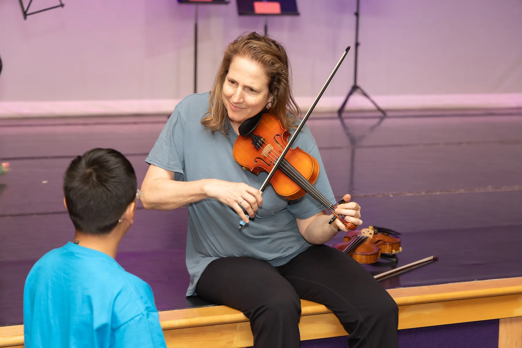 A violinist playing beside a young student